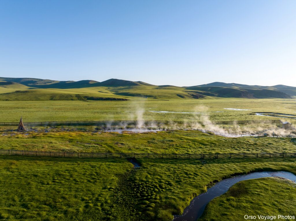 Vapeur des sources chaudes au creux d’une vallée verte, Mongolie