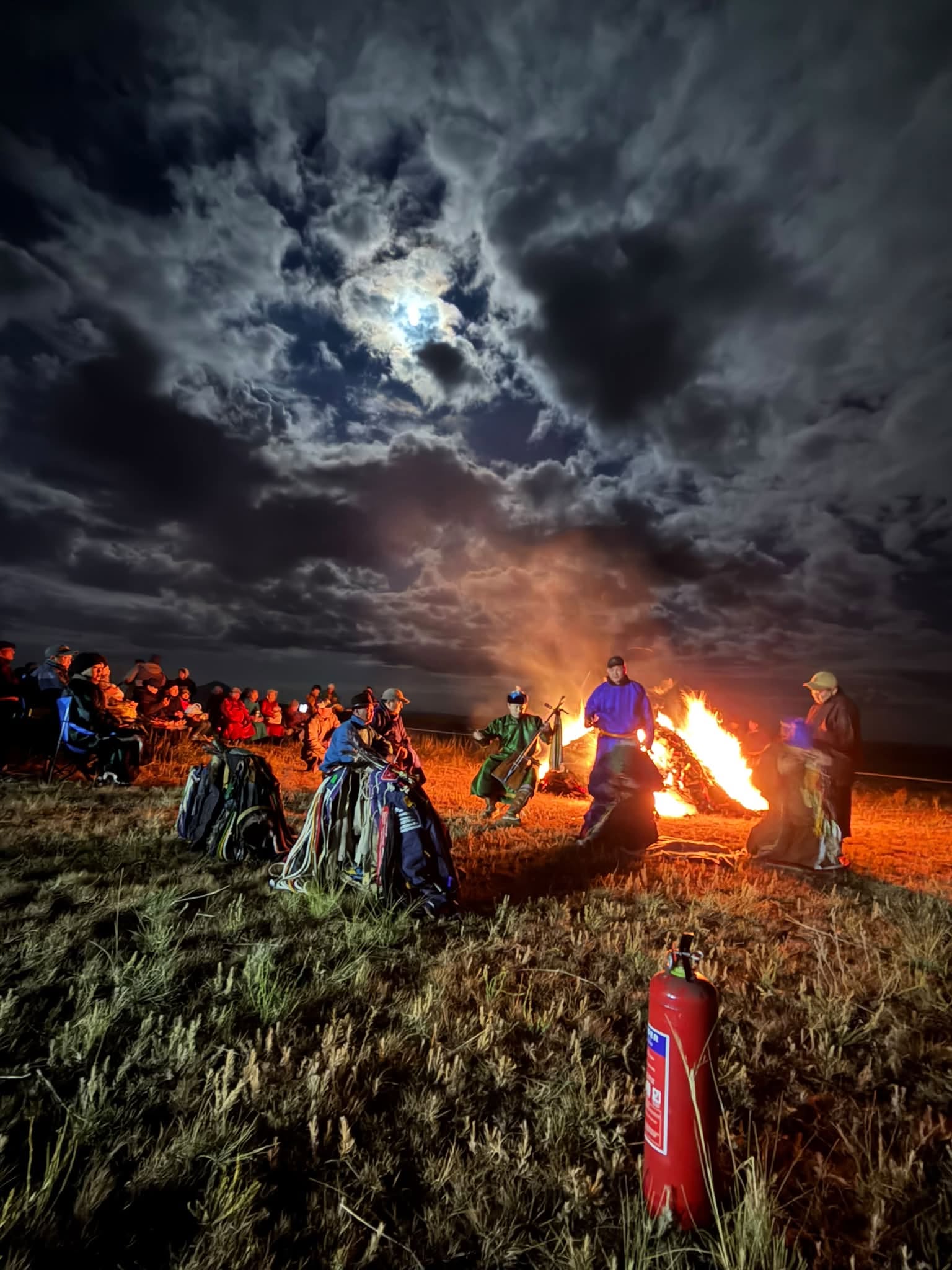 Cérémonie chamanique du feu de nuit dans la steppe mongole, chamanes en costume rituel et musicien au morin khuur sous la pleine lune